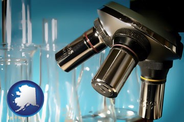 a microscope and glassware in a research laboratory - with Alaska icon