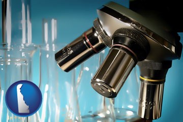 a microscope and glassware in a research laboratory - with Delaware icon