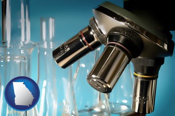 a microscope and glassware in a research laboratory - with Georgia icon