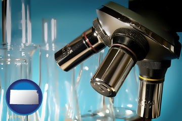 a microscope and glassware in a research laboratory - with Kansas icon