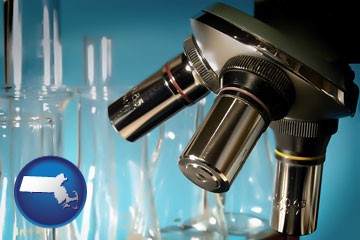 a microscope and glassware in a research laboratory - with Massachusetts icon