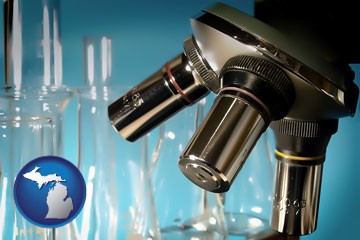 a microscope and glassware in a research laboratory - with Michigan icon