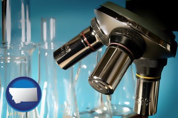 a microscope and glassware in a research laboratory - with Montana icon