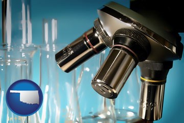 a microscope and glassware in a research laboratory - with Oklahoma icon