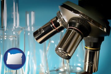 a microscope and glassware in a research laboratory - with Oregon icon