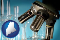 maine map icon and a microscope and glassware in a research laboratory